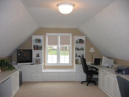 an attic office with desk, computer and bookshelf