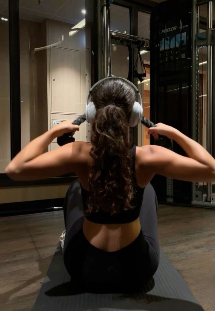 a woman sitting on the floor with headphones in her ears