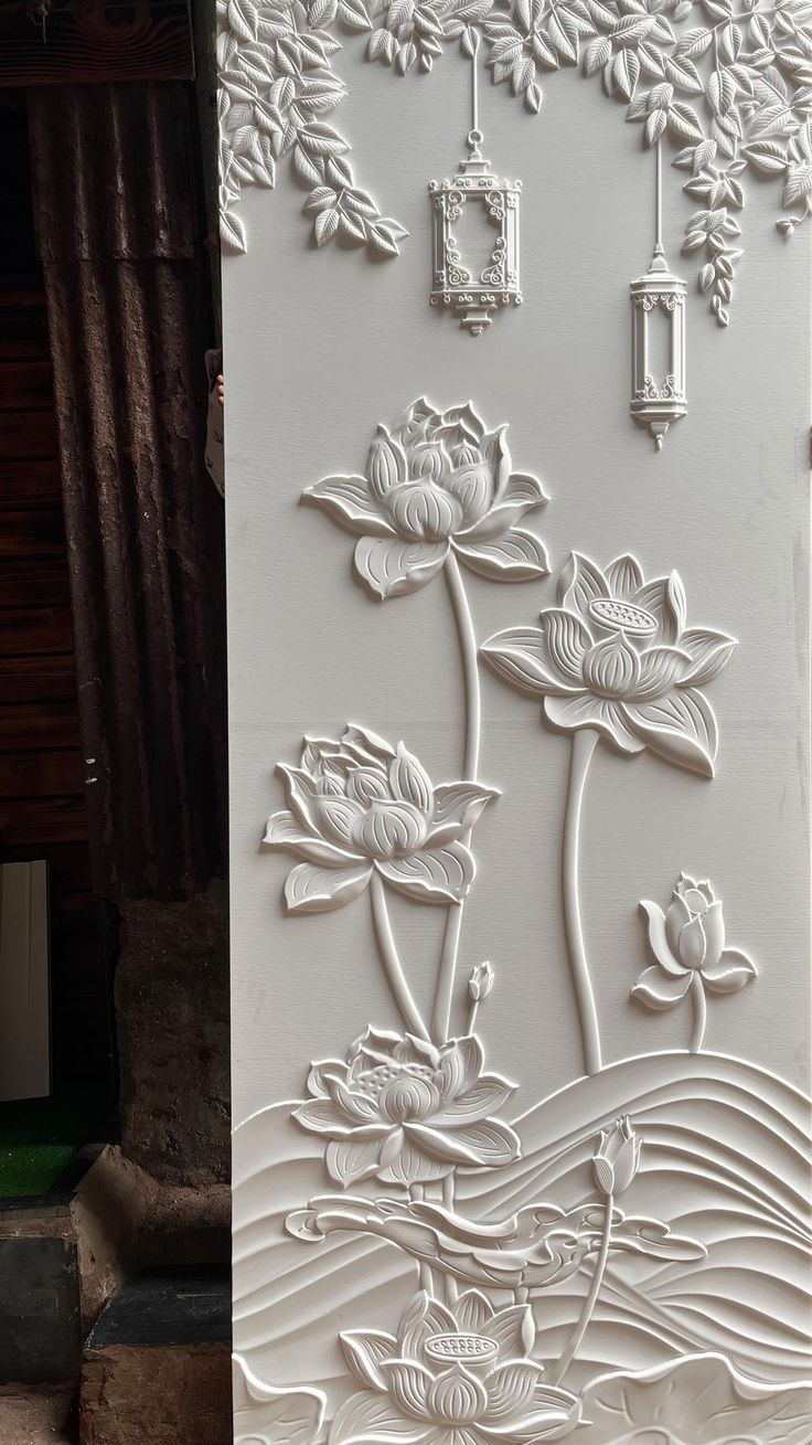 an intricately carved wall panel with flowers and leaves in white, on the outside of a building