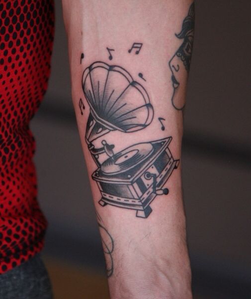 a person with a tattoo on their arm holding a record player