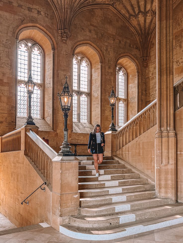 a woman is walking down the stairs in an old building