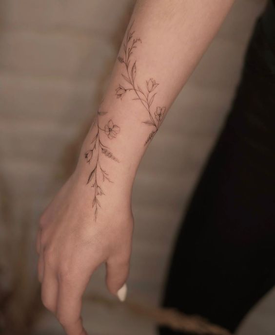 a woman's hand with a flower tattoo on her left wrist and the other arm