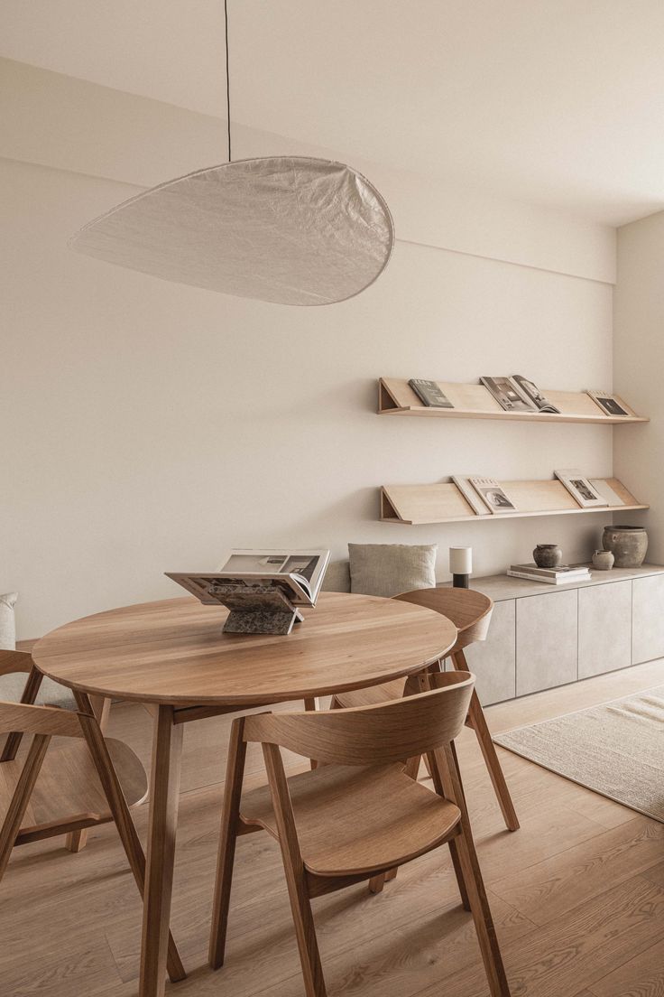 a dining room table and chairs in front of a window with bookshelves on the wall