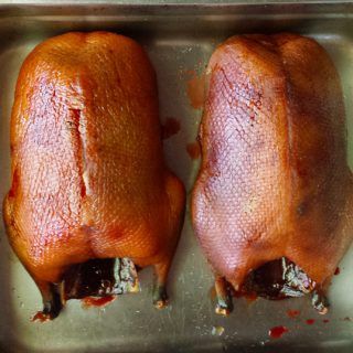 two raw chickens sit in a metal pan