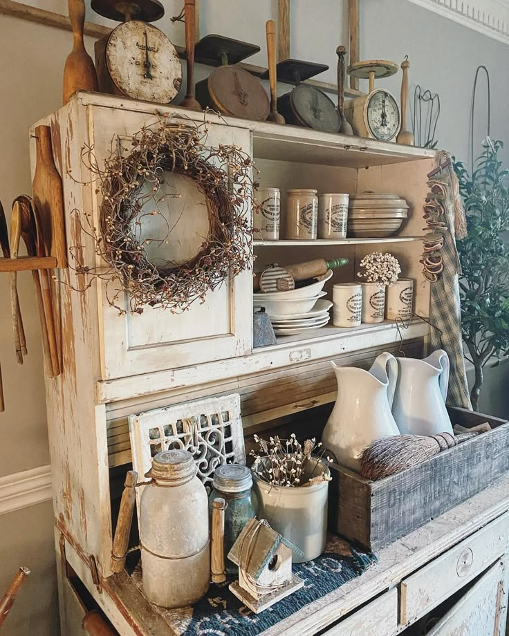 an old dresser with dishes and other items on it in a room that has white walls