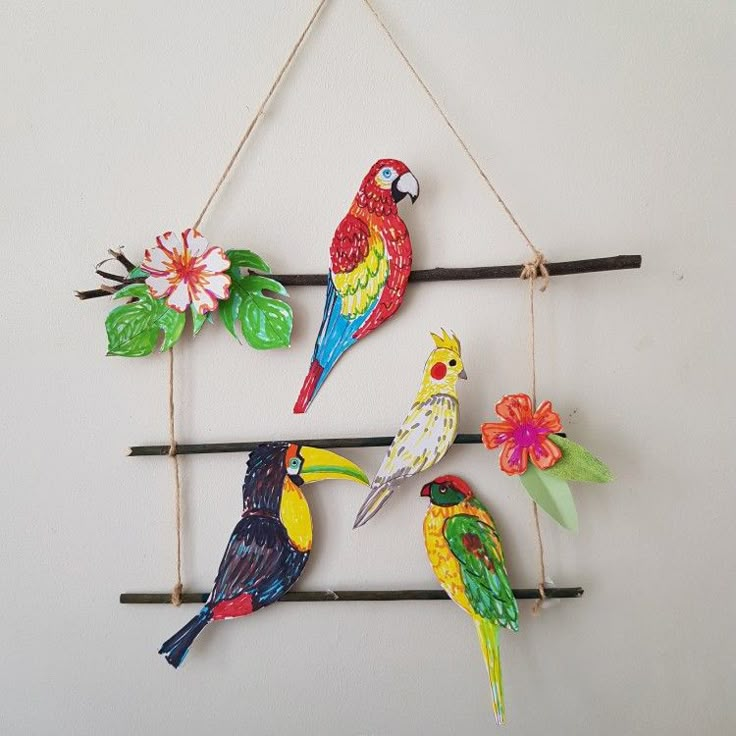 four colorful birds are hanging on the wall and one bird is perched on a branch