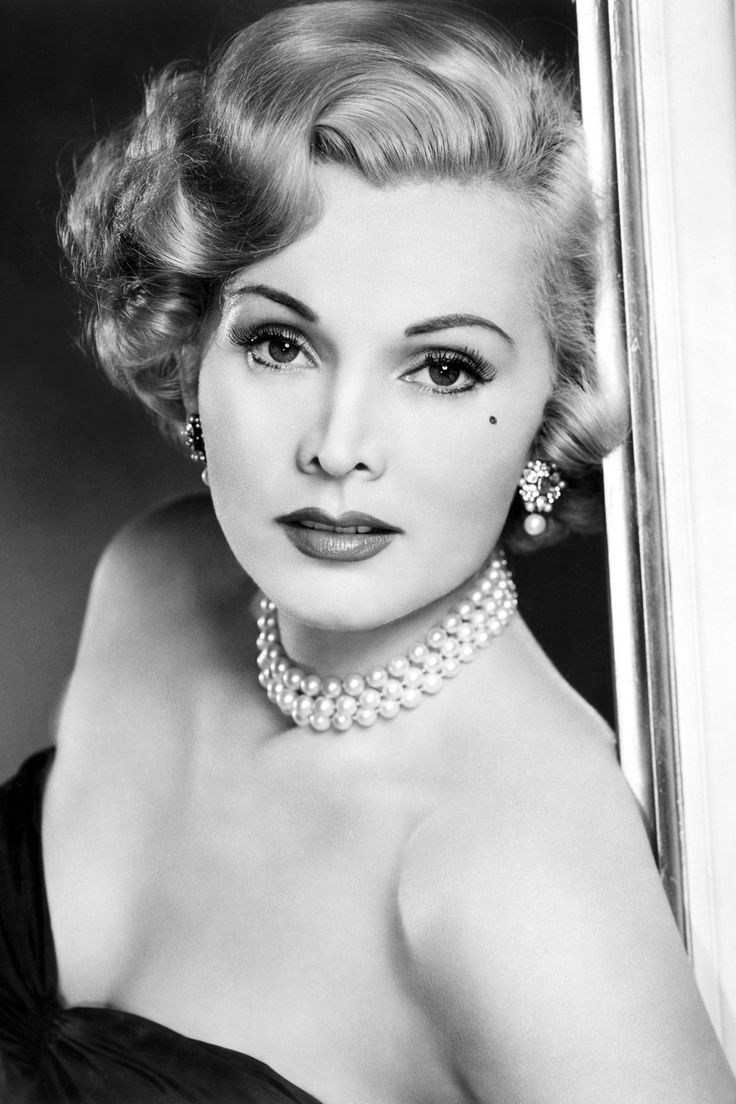 an old black and white photo of a woman in a dress with pearls on her neck