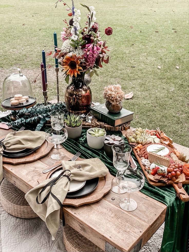 a table set up with plates, glasses and flowers in vases on top of it