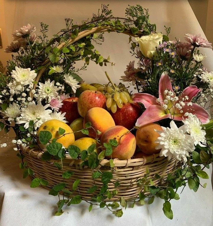 a basket filled with fruit and flowers on top of a table