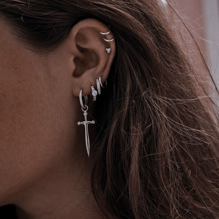 a close up of a person with ear piercings and a cross on their ear