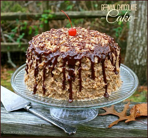 a cake with chocolate icing and nuts on top sitting on a glass platter