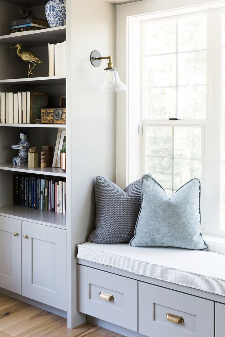 a window seat in front of a bookshelf filled with books