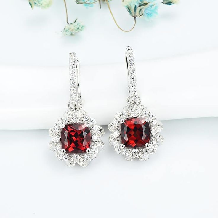 Features These Cushion Ruby Halo Sterling Silver Drop Earrings feature a classic and stylish design style suitable for any occasion.Made all by hand! It truly deserves a spot in every jewelry collection. Beautifully crafted, this style is sure to become a treasured keepsake. Each Ruby used for our jewelry was carefully checked and verified by our experts, so that they meet the highest standard. Providing high-quality items is our most important goal, which starts with selecting the best stones a Fine Jewelry Halo Design Drop Earrings, Halo Drop Earrings For Anniversary, Classic Drop Earrings With Halo Design, Classic Halo Design Drop Earrings, Formal Halo Drop Earrings, Halo Diamond Drop Earrings As Gift, Halo Dangle Earrings For Anniversary, Halo Design Bridal Drop Earrings For Gift, Classic Halo Drop Earrings