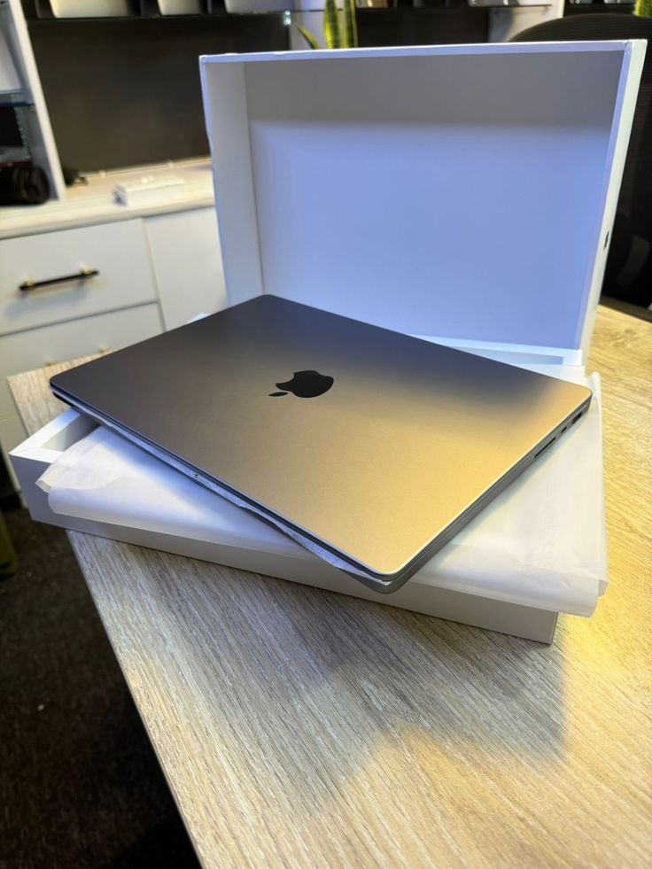 two open laptops sitting on top of each other in a white box with an apple logo