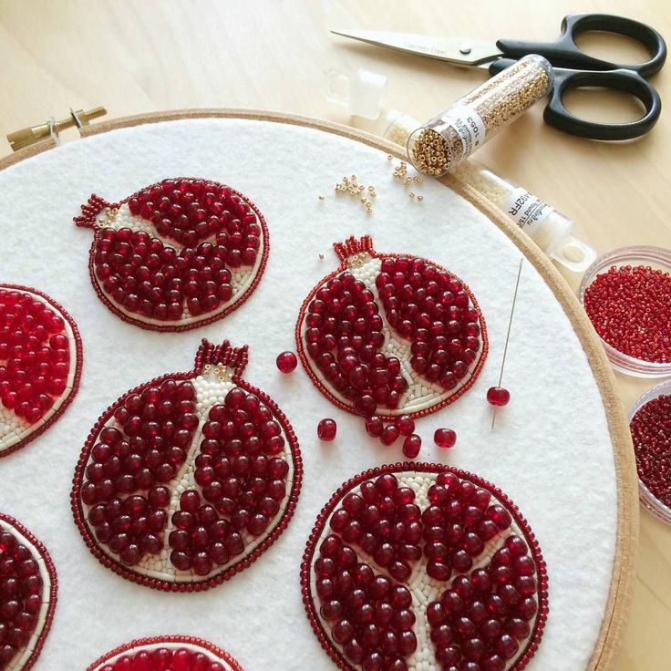 some red beads are being sewn together to make ornaments