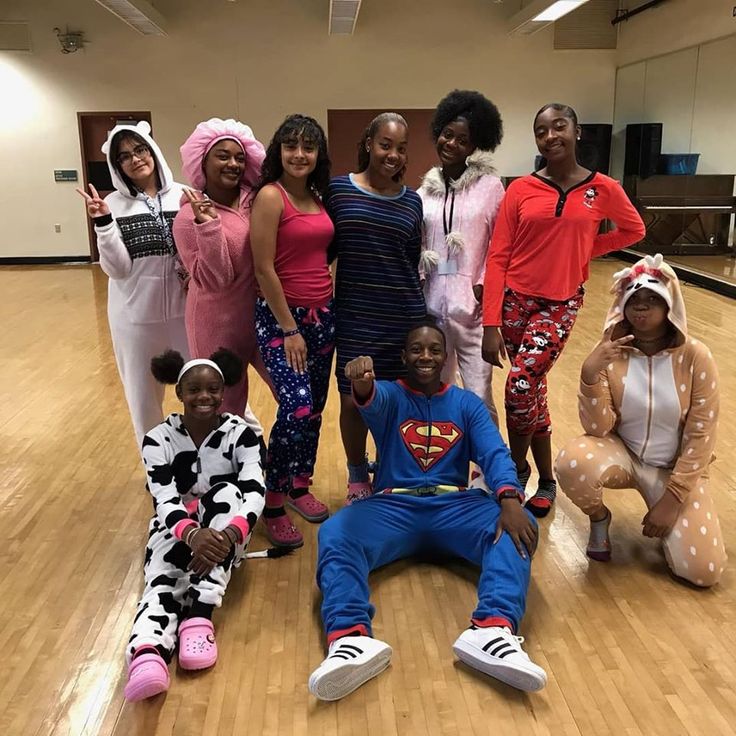 a group of people standing and sitting on top of a hard wood floor in pajamas