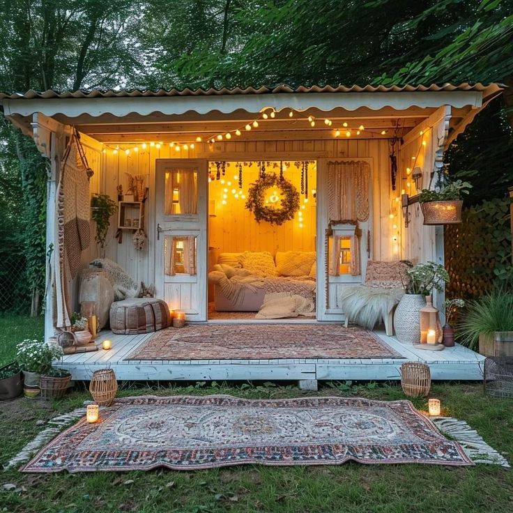 a small white shed with lights on the roof and bed in it's corner