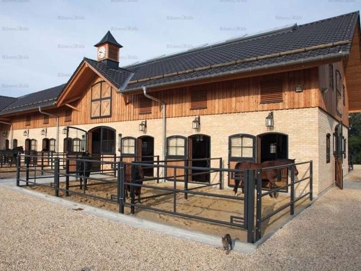 the building has horses in it and is made out of wood with metal railings