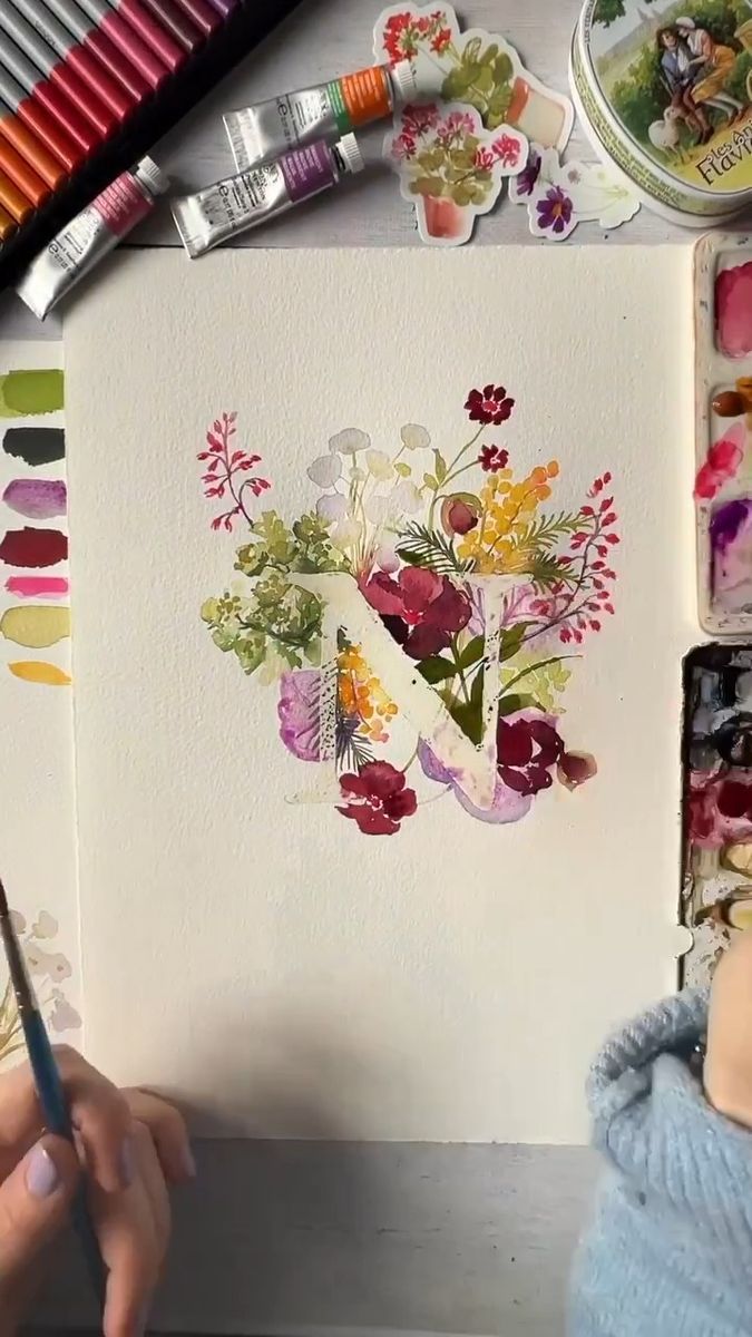 someone is painting flowers on paper with watercolors and crayon pencils