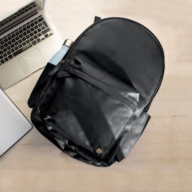 Our re-designed Classic Backpack now has ample space for a 15" laptop, and we've even given it it's own padded laptop compartment so you can stay organised. We've also added two external water bottle holders, complete with a waterproof lining, and a handy leather strap on the back that slots over wheelie suitcase handles so you can give your back a rest when you're on the go. -handmade to order -30 day money-back guarantee. $1.50 from every sale is donated to FRANK Water. Waterproof Black Leather Bags, Waterproof Leather Shoulder Bag For Travel, Casual Leather Waterproof Backpack, Casual Leather Backpack Waterproof, Everyday Leather Waterproof Bag, Urban Style Waterproof Bags For Everyday Use, Casual Leather Backpack For Travel With Zipper Pocket, Modern Coated Canvas Backpack For Travel, Urban Waterproof Bags For Everyday Use