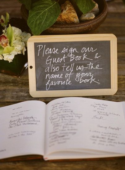 an open book sitting on top of a wooden table next to a potted plant