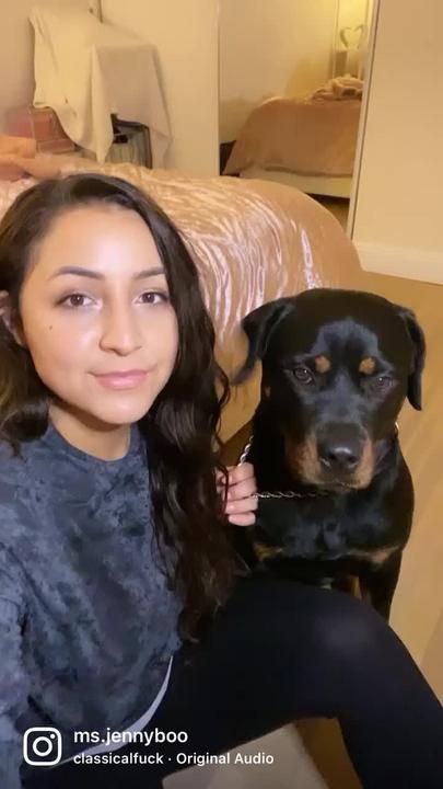 a woman sitting on top of a couch holding a black and brown dog in her lap