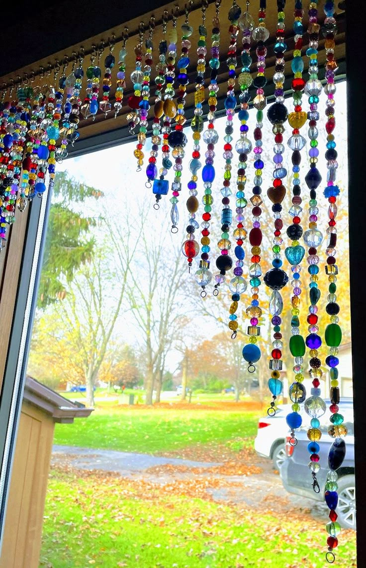 a window with beads hanging from it's side and a car parked in the background