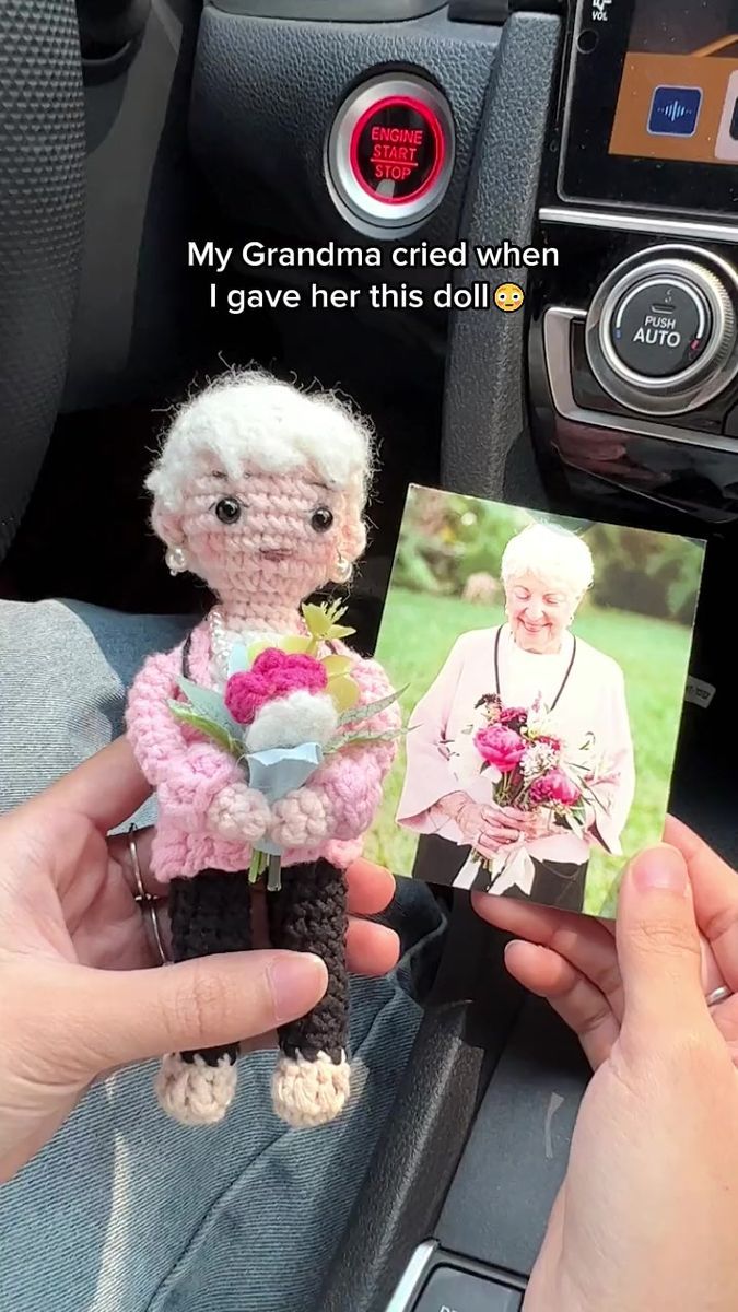 a person holding a small stuffed animal in their hand next to a car dash board