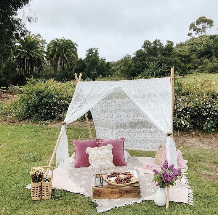 a white canopy bed sitting on top of a lush green field