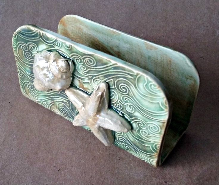 a green ceramic container with two shells on it