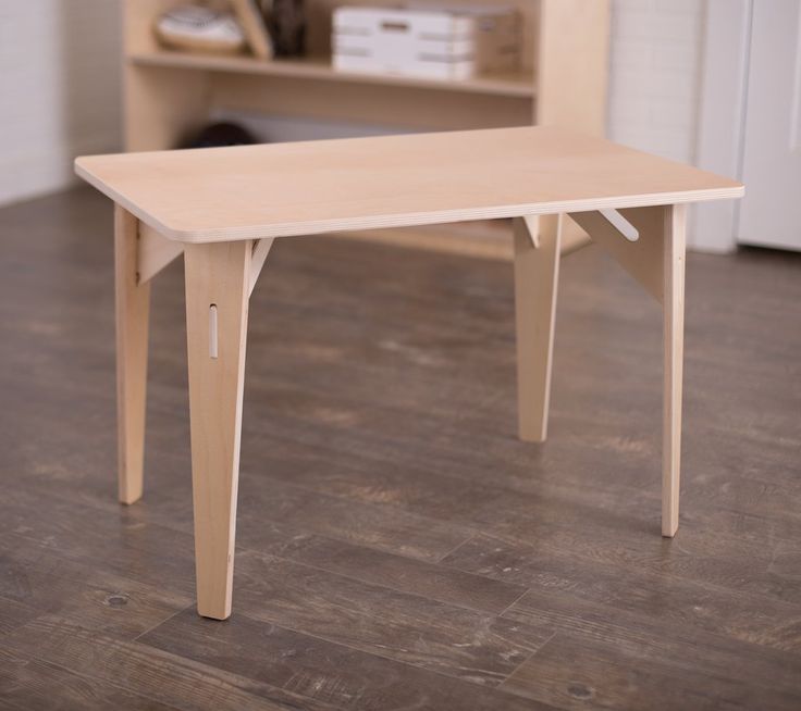 a white table sitting on top of a hard wood floor next to a book shelf