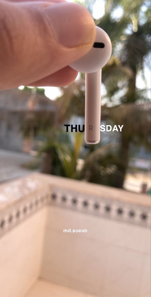 a hand holding an electronic device in front of a building with the words thursday written on it