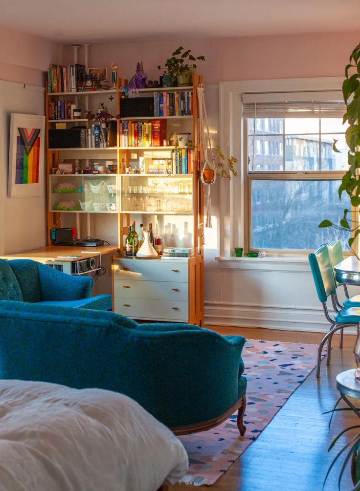 a living room filled with lots of furniture and bookshelves next to a window