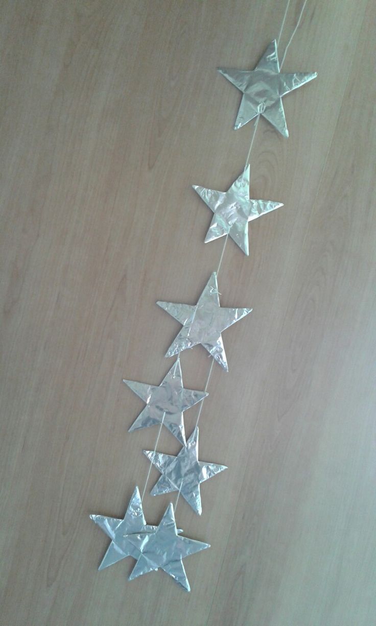 three silver stars hanging from strings on a wooden surface