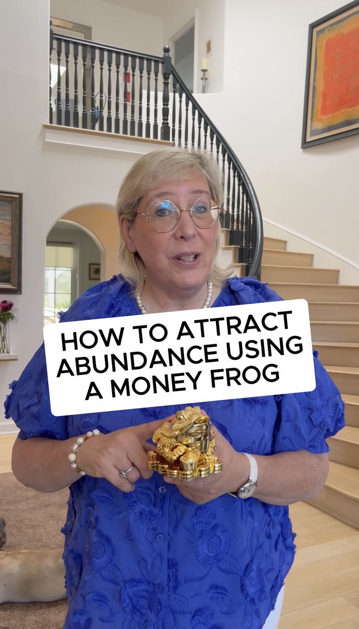 a woman holding a sign that says how to attract abundance using a money frog