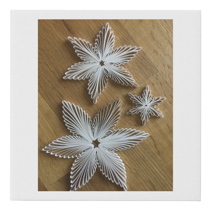 three white paper flowers sitting on top of a wooden table