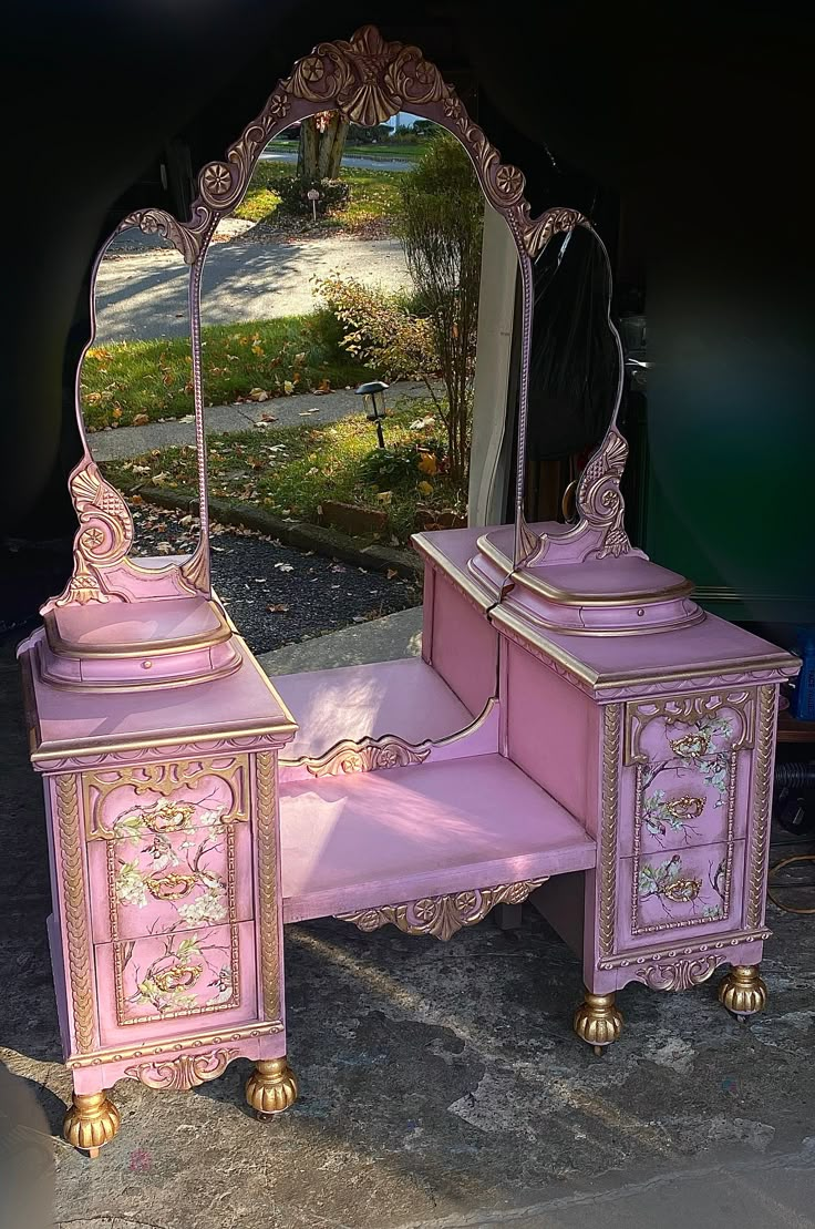 an antique pink vanity with mirror and stool