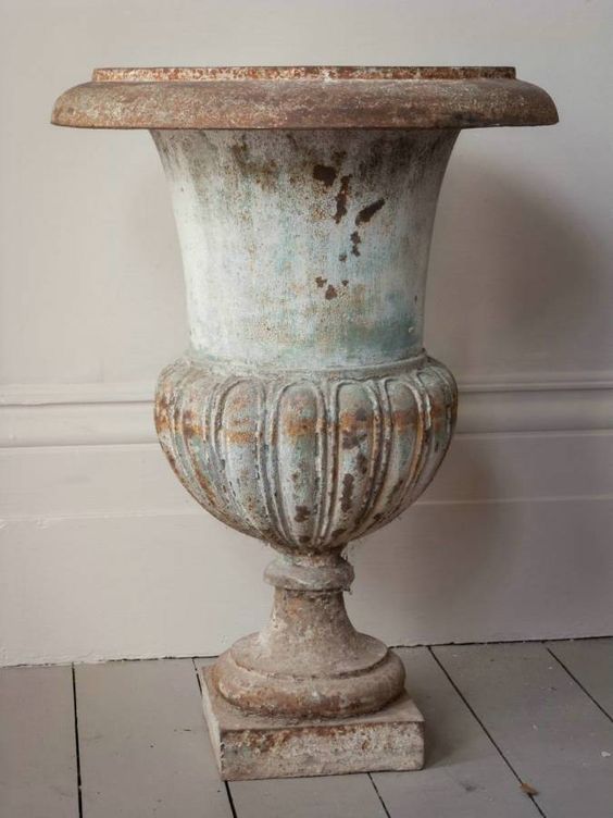 an old vase sitting on top of a wooden floor next to a wall and white walls