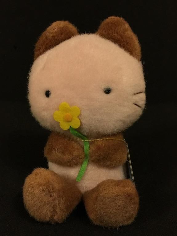 a teddy bear with a yellow flower in its mouth sitting on a black background,