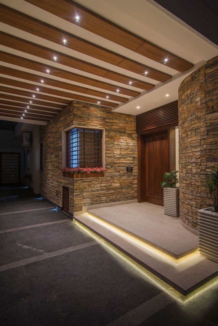 an indoor area with stone walls and plants on the steps leading up to the front door