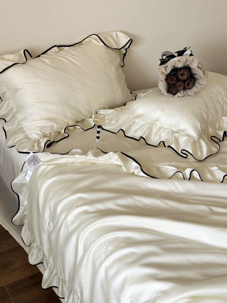 an unmade bed with white sheets and black ruffles