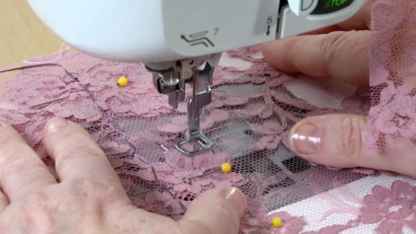 an older woman using a sewing machine to sew lace