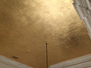 the ceiling is painted gold and there are two lamps on each side of the room