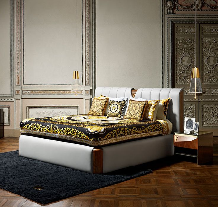 a large bed sitting on top of a wooden floor next to a night stand and lamp