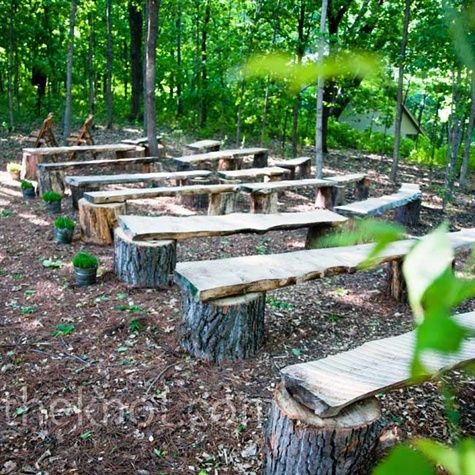 several wooden benches sitting in the middle of a forest