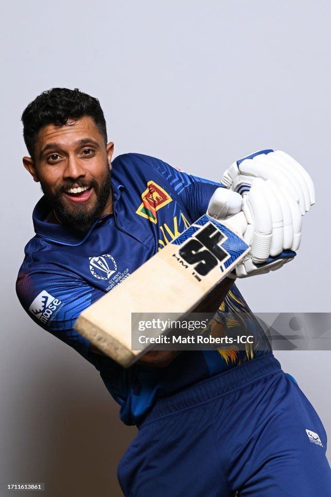 a man holding a cricket bat in his hands and smiling at the camera, against a gray background