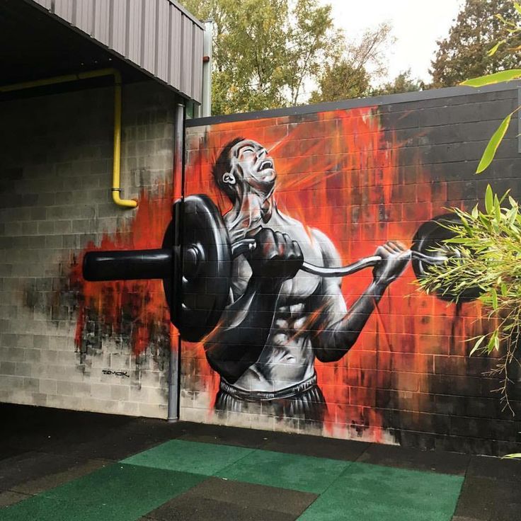 a mural painted on the side of a building depicting a man lifting a barbell