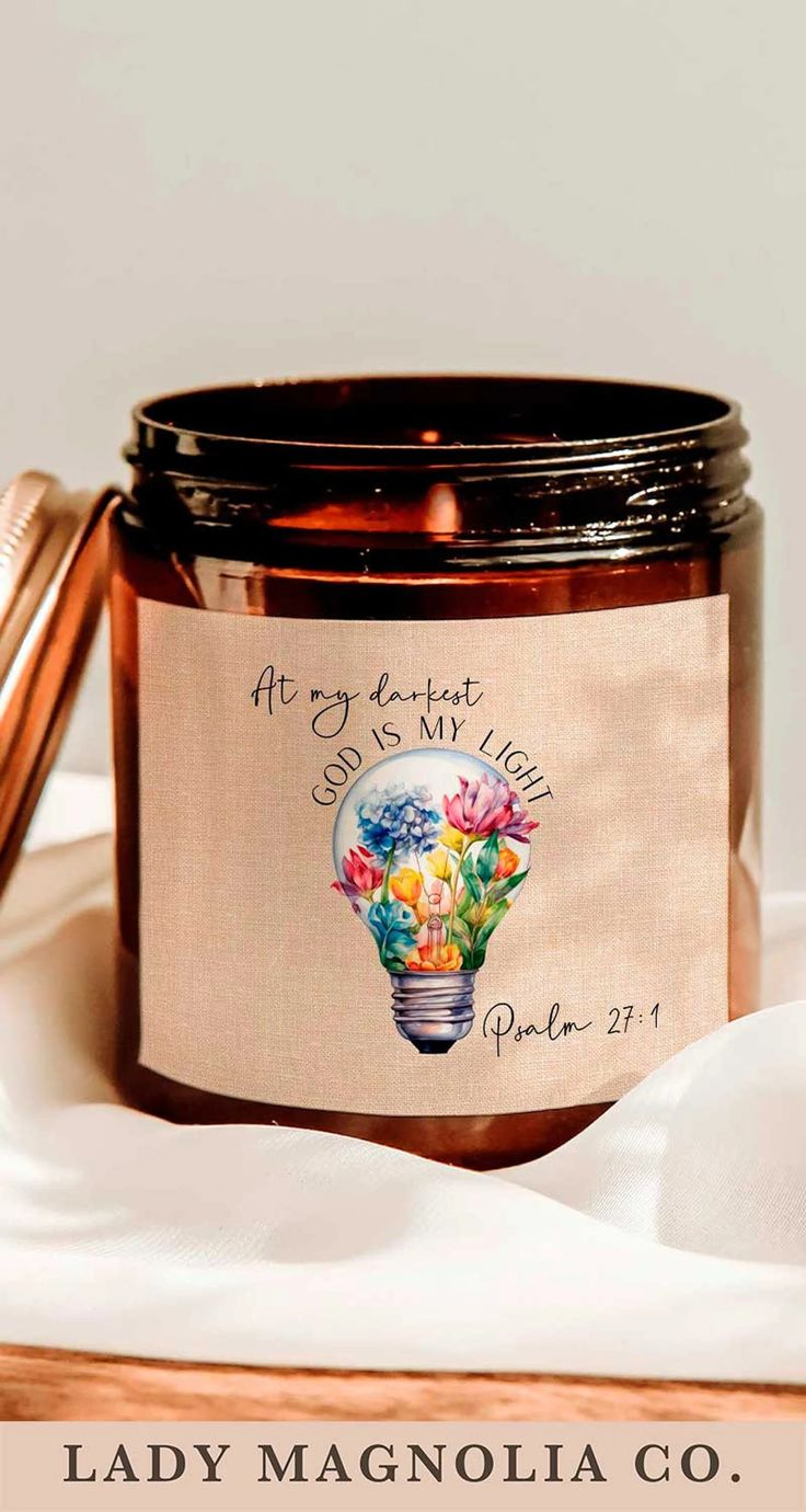 a candle with a label on it sitting on top of a white cloth covered table