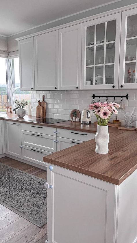 a kitchen with white cabinets and wooden counter tops, along with an area rug on the floor