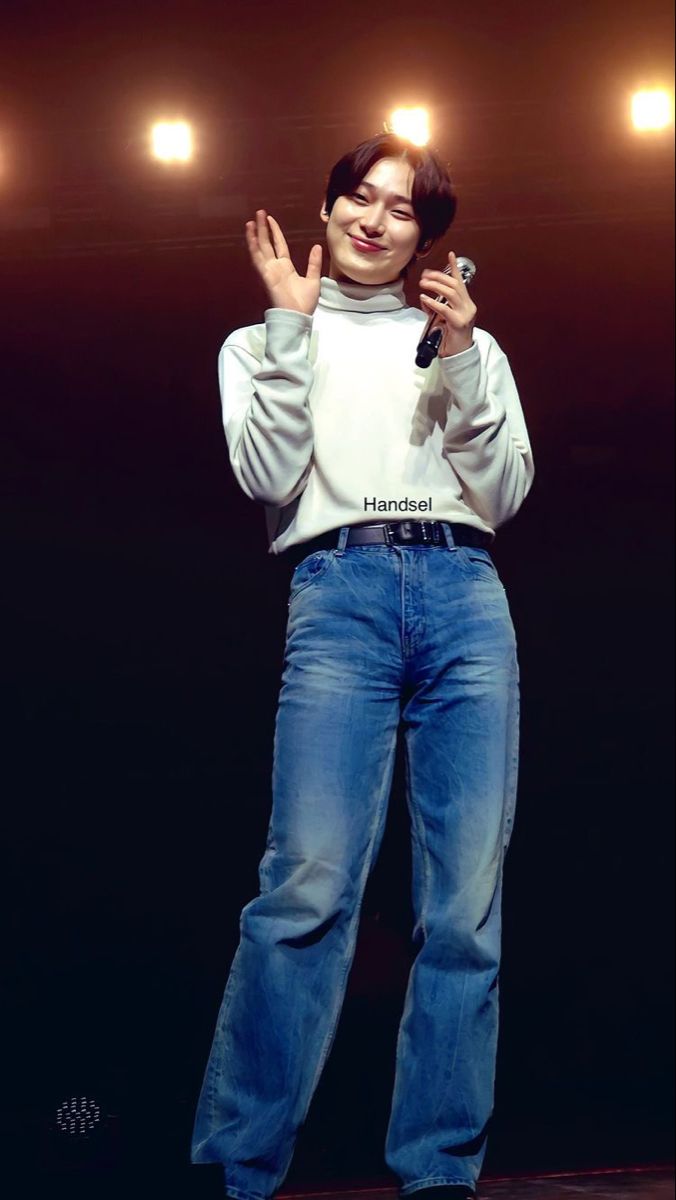 a man standing on top of a stage with his hands in the air while holding a microphone